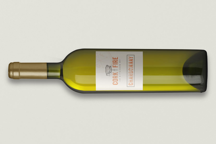 Bottle of Chardonnay with a Cork | Fire Kitchen label, featuring a pig illustration and bold orange typography on a white background.
