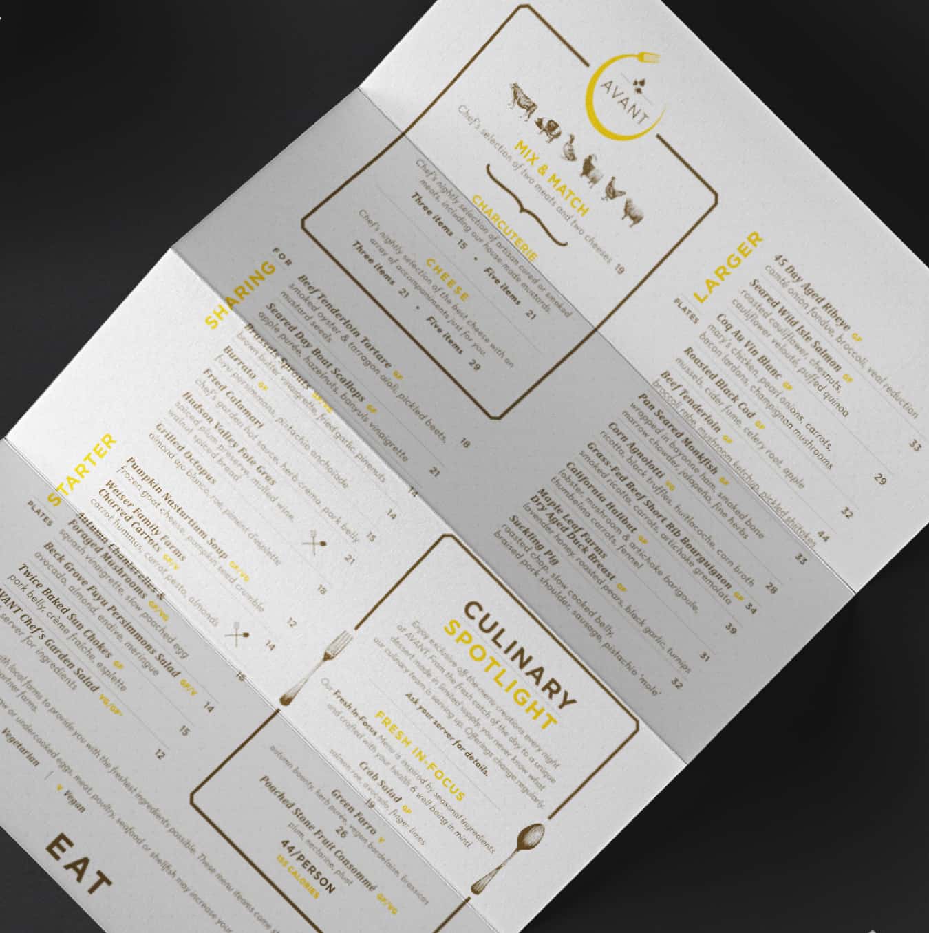 A trifold menu for 'AVANT' restaurant open on a tabletop, showing various gourmet food options categorized under starters, mains, and culinary specials.