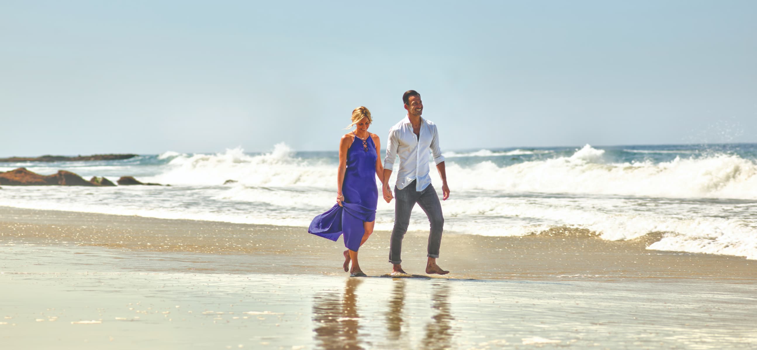 A couple walk hand-in-hand along the beach at the Surf & Sand Resort